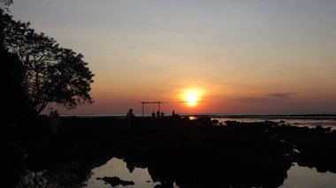 Endonezya 'da okyanus üzerinde dramatik bulutlarda düşük turuncu gün batımı