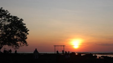 Endonezya 'da okyanus üzerinde dramatik bulutlarda düşük turuncu gün batımı