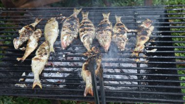 Masanın üzerine acı biber serpiştirilmiş lezzetli ızgara balık servis edilir.