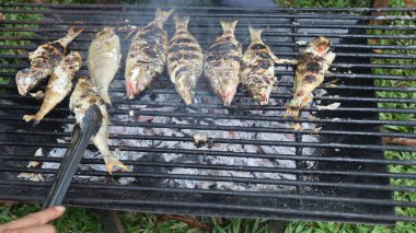 Masanın üzerine acı biber serpiştirilmiş lezzetli ızgara balık servis edilir.