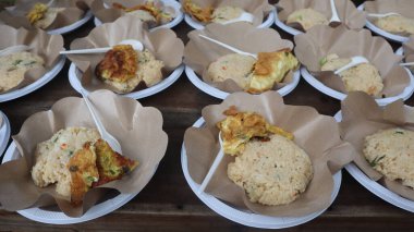 Beyaz bir tabakta servis edilen kızarmış patates pilavı, kızarmış tavuk parçaları ve sebzeler.