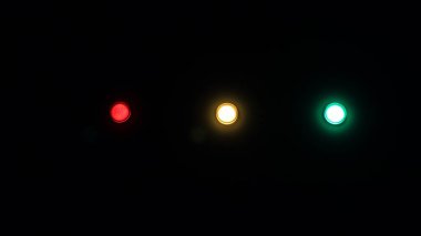 Elektrik panelindeki ışıklar, kırmızı, sarı ve yeşil. Siyah arkaplan.