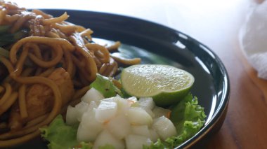 Ahşap masada servis edilen kızarmış erişteler.