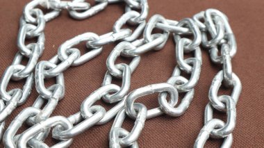 Kahverengi zemin üzerinde çelik zincir, birbirine bağlı çelik zincir.