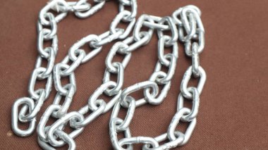 Kahverengi zemin üzerinde çelik zincir, birbirine bağlı çelik zincir.