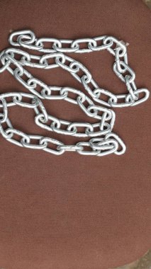 Kahverengi zemin üzerinde çelik zincir, birbirine bağlı çelik zincir.