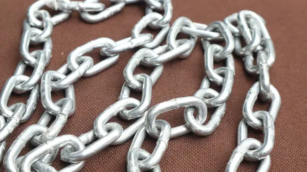Kahverengi zemin üzerinde çelik zincir, birbirine bağlı çelik zincir.