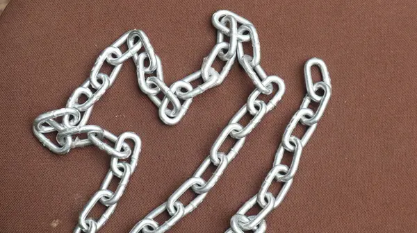 Kahverengi zemin üzerinde çelik zincir, birbirine bağlı çelik zincir.