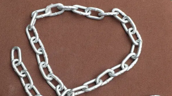 Kahverengi zemin üzerinde çelik zincir, birbirine bağlı çelik zincir.