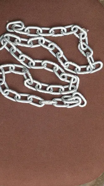 Kahverengi zemin üzerinde çelik zincir, birbirine bağlı çelik zincir.