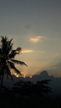 Yoğun karanlık bulutları delip geçen, tropikal ormanları ve uzak dağları aşan güneş ışınlarıyla dramatik bir manzara. Umut, barış, doğa ve maneviyat teması için ideal..