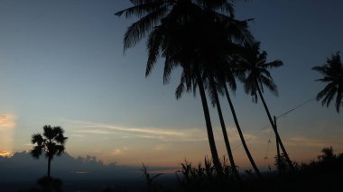 Yoğun karanlık bulutları delip geçen, tropikal ormanları ve uzak dağları aşan güneş ışınlarıyla dramatik bir manzara. Umut, barış, doğa ve maneviyat teması için ideal..