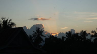 Yoğun karanlık bulutları delip geçen, tropikal ormanları ve uzak dağları aşan güneş ışınlarıyla dramatik bir manzara. Umut, barış, doğa ve maneviyat teması için ideal..