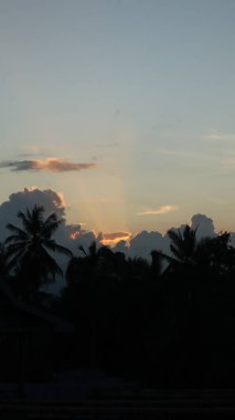 Yoğun karanlık bulutları delip geçen, tropikal ormanları ve uzak dağları aşan güneş ışınlarıyla dramatik bir manzara. Umut, barış, doğa ve maneviyat teması için ideal..