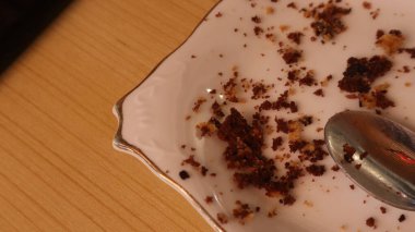 chocolate cake remains on a white plate on a brown table