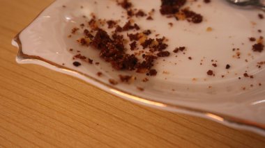 chocolate cake remains on a white plate on a brown table