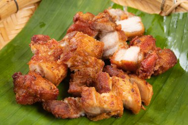 Bol yağda kızartılmış domuz eti ve muz yaprağına balık sosu..