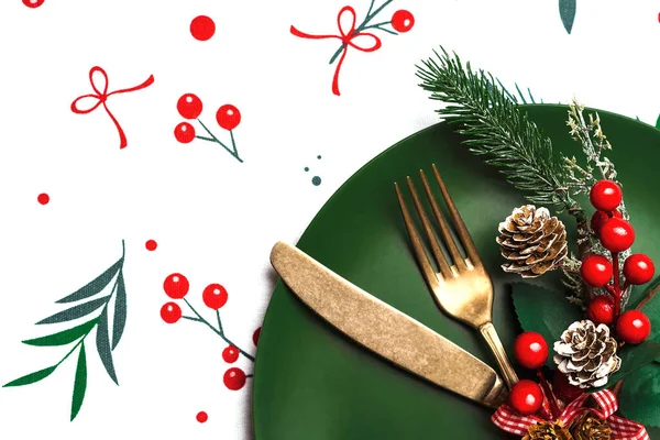 Christmas dinner concept. Vintage old cutlery and christmas ornament on a plate over christmas tablecloth. Christmas concept background