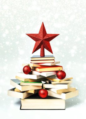 Noel konsepti geçmişi. Yılbaşı baloları ve Noel ışıkları ve kar taneleri üzerine kırmızı yıldızlı yılbaşı ağacı şeklinde kitaplar.