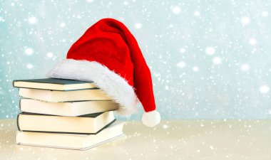 Mutlu noeller. Noel Baba 'nın şapkası, kitaplar, kar taneleri ve mavi arkaplandaki yazılar için yer. Noel konsepti geçmişi