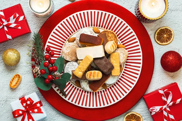 stock image Top view of Nougat christmas sweet,mantecados and polvorones on a plate with christmas ornaments over a white background. Assortment of christmas sweets typical in Spain