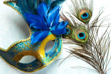 Venetian carnival mask and peacock feathers over blue background. Carnival celebration concept