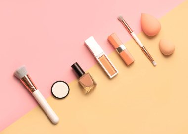 Makyaj fırçaları, göz farı, güzellik makyajı süngerleri, sarı ve pembe arka planda tırnak cilası ve ruj. Güzellik ve makyaj konsepti 