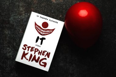 Close-up of the book in spanish It by American novelist Stephen King and red balloon over grunge background clipart