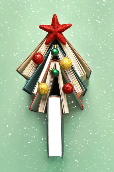 クリスマスのコンセプト背景 クリスマスツリーの形の本 緑の背景と雪片の上のクリスマスボールと赤い星 ストックフォト