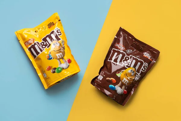 青と黄色の背景にチョコレートとピーナッツのM Mのパックのクローズアップショット イラストエディタ ロイヤリティフリーのストック画像
