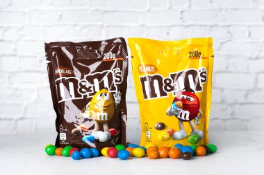 Beyaz bir masanın üzerinde M & M çikolata ve fıstık paketleri yakın plan. İllüstrasyon Editörü