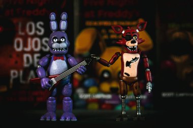 Figures of Bonnie and Foxy characters of the videogames,movies and books Five Nights at Freddy's in front of books. Illustrative editorial clipart