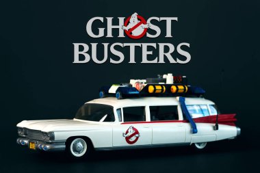 Playmobil car from the movie Ghostbusters with the Ghostbusters logo above over black background. Illustrative editorial clipart