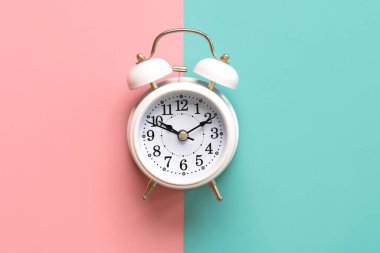 Pembe ve mavi arkaplan üzerindeki beyaz alarmlı saatin üst görünümü