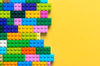 Renkli lego bloklarını kapatın ve sarı arkaplanda metin için boşluk bırakın. İllüstrasyon Editörü
