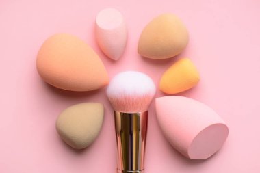 Makyaj fırçası ve makyaj malzemelerinin üst görüntüsü pembe arka planda. Güzellik ve makyaj konsepti