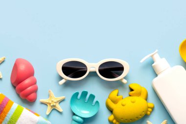 Güneş gözlüklerinin, denizyıldızlarının, güneş kreminin ve plaj oyuncaklarının mavi arkaplandaki yazılar için fotokopi alanı var. Yaz tatili kavramı