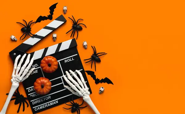 stock image Halloween movies concept. Movie clapperboard with skeleton hands,funny halloween pumpkins and spiders with copy space for text over orange background. Halloween concept background