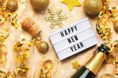 Mutlu yıllar 2025. Işıkkutusunun en iyi görüntüsü. Mutlu yıllar 2025, kristal bardaklar ve altın parıltılı masa örtüsü üzerinde altın noel topları. Yeni yıl kutlamaları konsepti