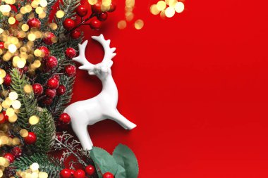 Beyaz Ren geyiği, kırmızı böğürtlen dalları ve kırmızı arkaplanda yazı için yeri olan yılbaşı ışıkları. Noel konsepti geçmişi