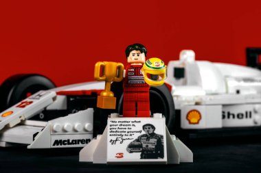 Ayrton Senna Lego figürü Brezilya Formula 1 yarış pilotu Formula 1 arabasının yanında McLaren MP4 / 4 kırmızı arka planda.