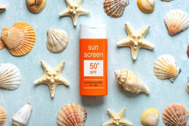 Top view of bottle of sunscreen with 50+ written on it and starfishs over blue background. Concept of sun protection