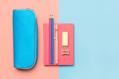 Pembe not defterli kalem kılıfının en üst görüntüsü ve mavi ve pembe arkaplanlı metinler için okul malzemeleri. Okul konseptine dönelim.