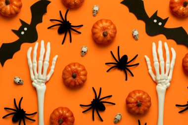 İskelet el kemikleri ve turuncu arka planda Cadılar Bayramı partisi dekorasyonunun en üst görüntüsü. Cadılar Bayramı konsepti