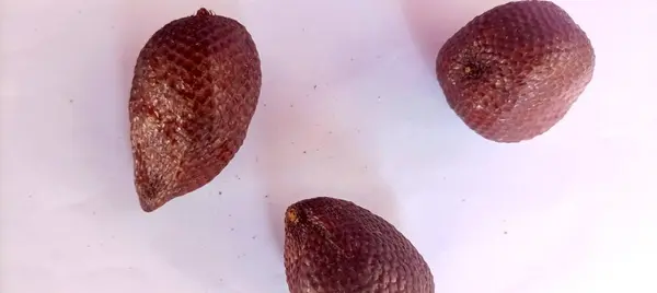Beyaz arkaplanda yılan derisi gibi meyvelerin fotoğrafı var.