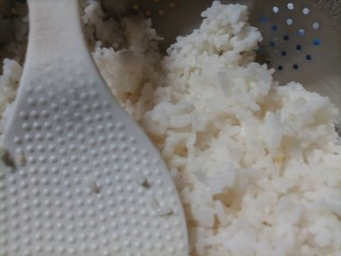 Yakın plan taze pişmiş beyaz pirinç. Bu resim, bu temel gıdanın narin dokusunu ve iştah açıcı görünümünü gösteriyor..