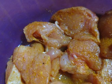 Kızartmaya hazır sarı baharatlı mavi bir havuzda çiğ tavuk..