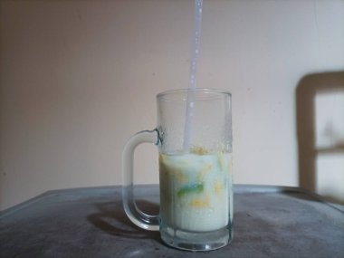 Mutfak masasındaki büyük beyaz bardaktaki buzlu avokado sütü..