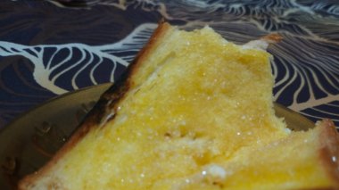 Küçük bir tabakta servis edilen tereyağlı tostun yakın çekimi..