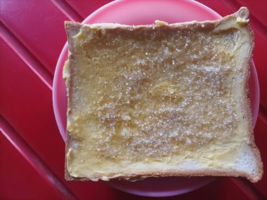 Kahvaltı. Sarı tereyağlı beyaz ekmek. Üzerine şeker serpiştirilmiş..